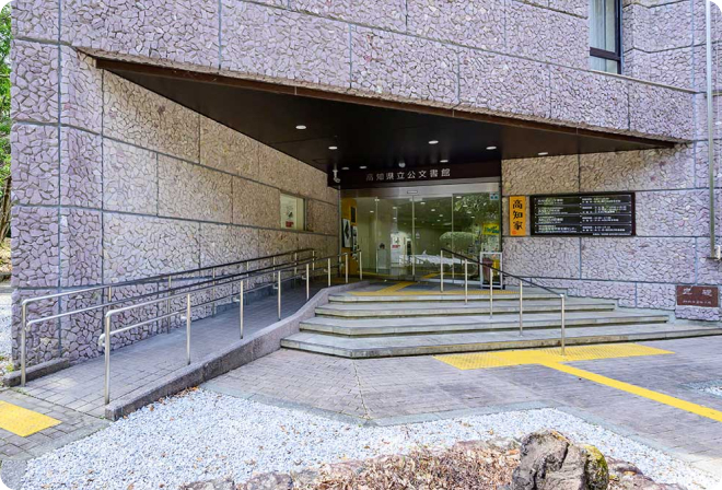 写真：高知県公文書館の建物入り口。階段の隣に手すり付きのスロープがあります。入り口は自動ドアです。