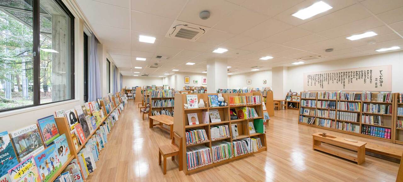 写真：図書館の中の様子。本棚にたくさんの本が並んでいます。壁には絵や詞が飾ってあります。木でできた椅子があります。