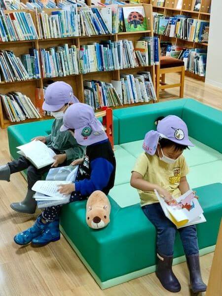 写真：帽子をかぶったこどもたちが館内で絵本を読んでいます。