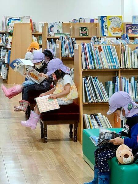 写真：帽子をかぶったこどもたちが館内で絵本を読んでいます。