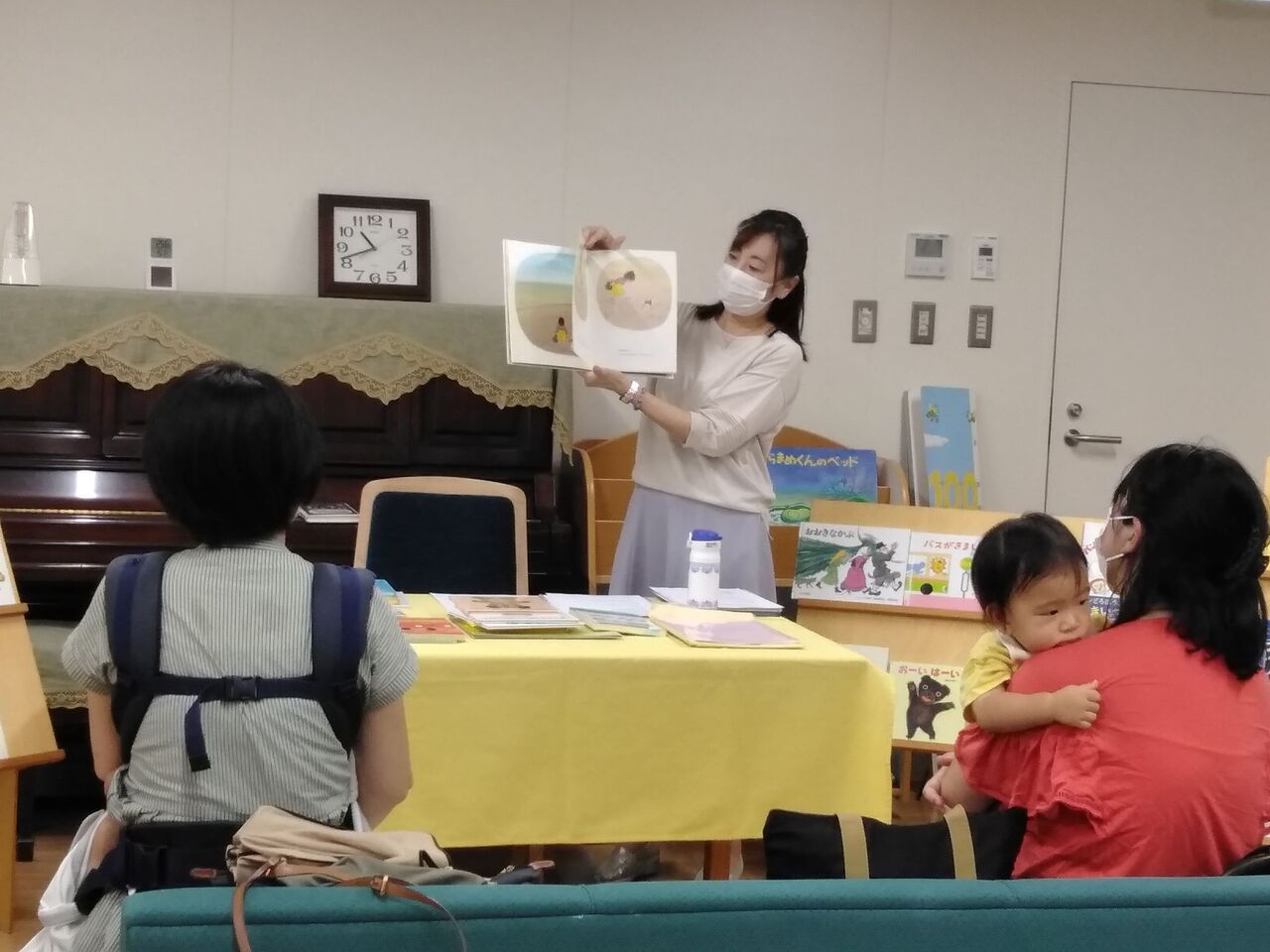 写真：清水果子さんが小さいお子さん連れの親子に絵本を読み聞かせています。