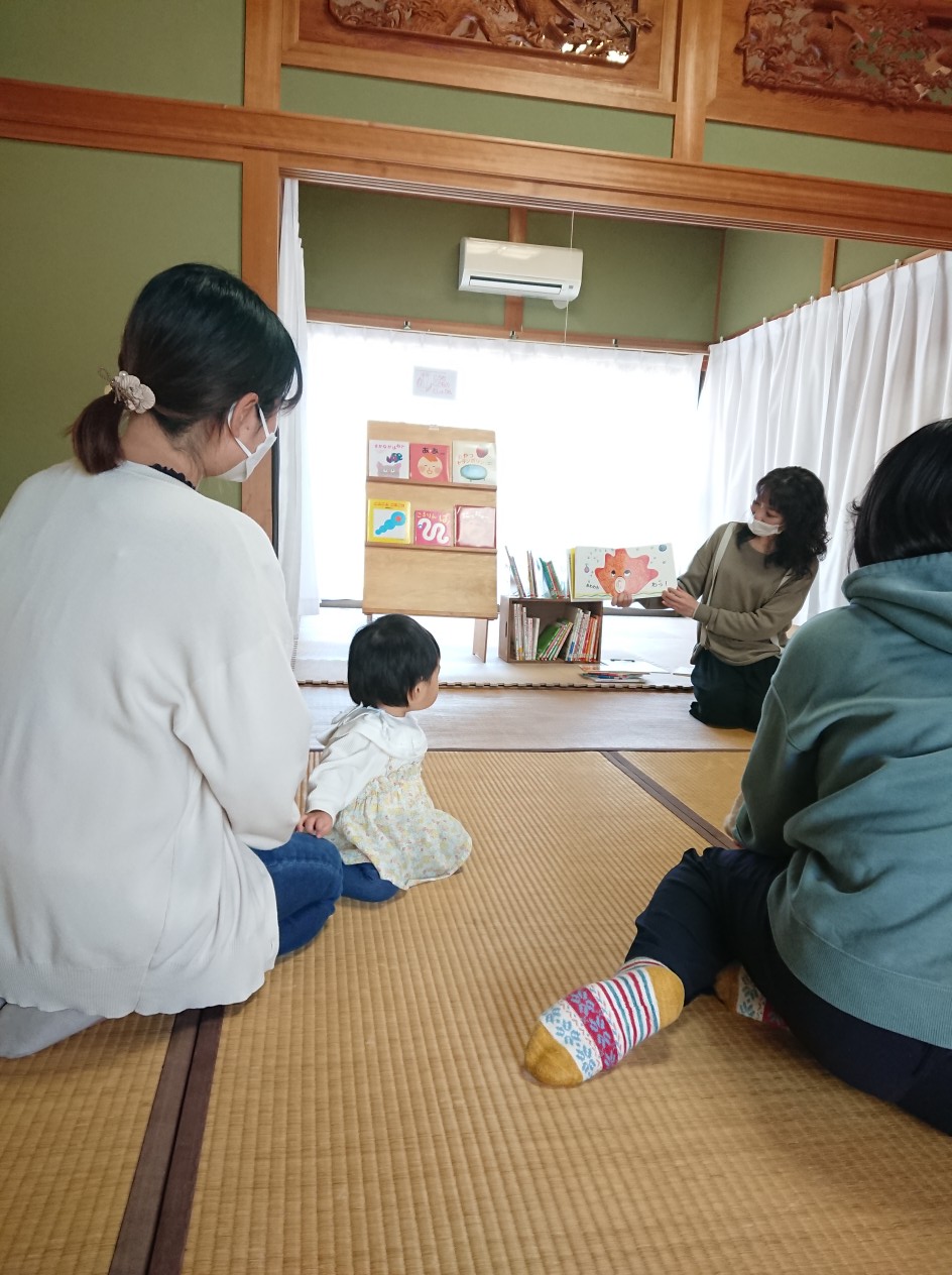 写真：ママアナ尾崎さんが赤ちゃんに絵本を読み聞かせしています。