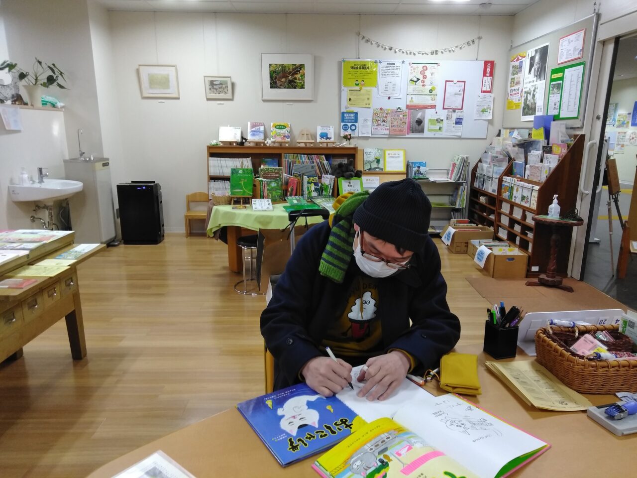 写真：絵本にサインを書いている絵本作家の大塚健太さんです。