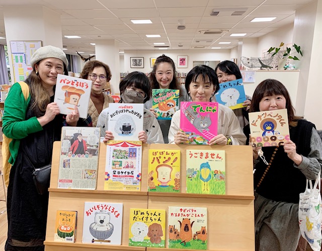 写真：柴田ケイコさんとお客様、スタッフが柴田さんんの絵本を持って並んでいます。