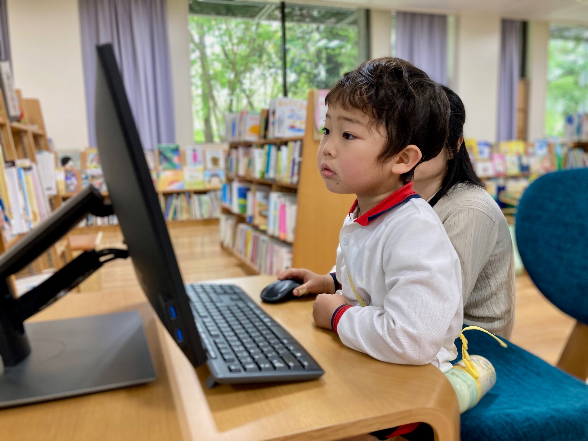 写真：男の子がパソコンで本を検索しています。