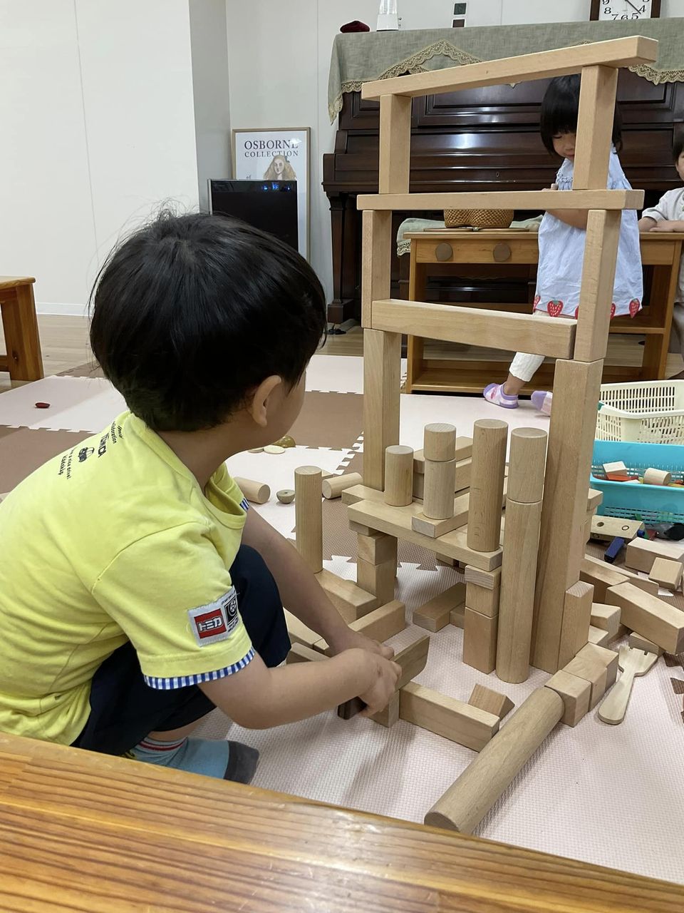 写真：男の子が積み木で大きなタワーを作っています。