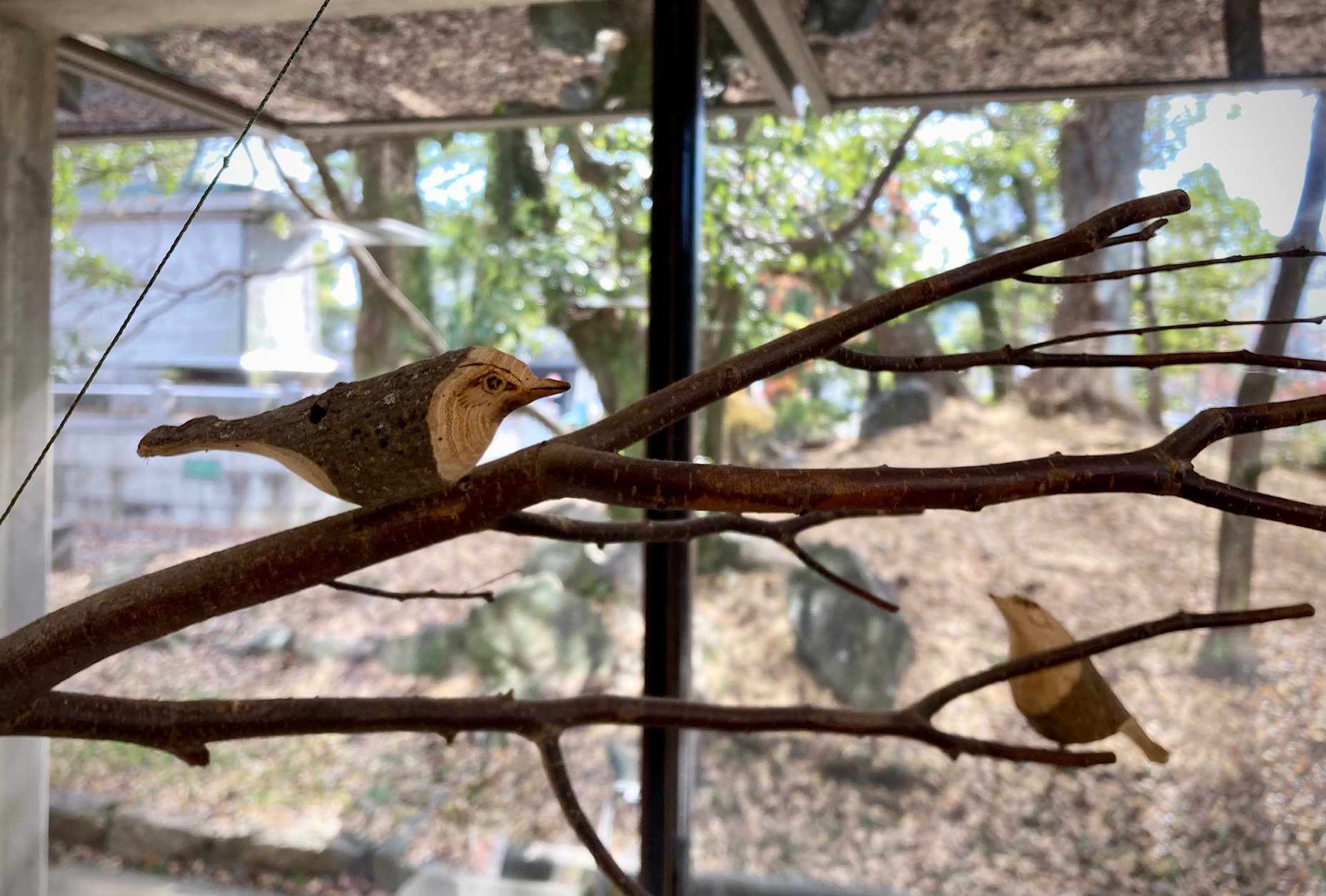 写真：館内の天井に吊り下げられた木の枝と、枝に止まる木の鳥です。