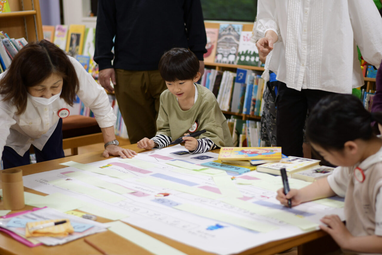 写真:ペンを持って模造紙を見つめる男の子です