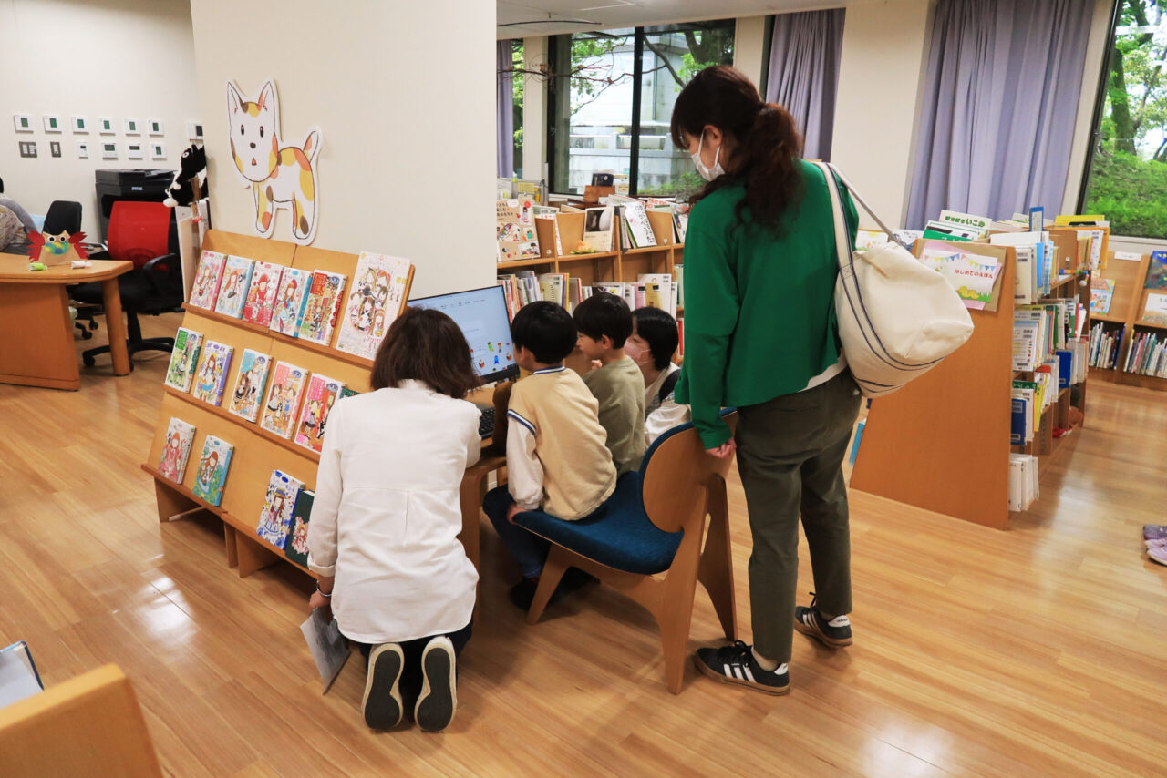 写真:図書館のパソコンを見るこどもと大人たちです