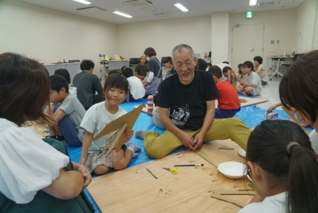 写真：あべ弘士さんと子どもたちがダンボールでキリンを作っています。