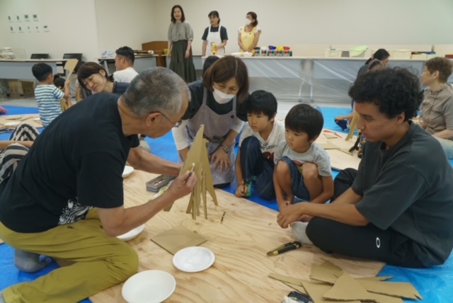 写真：あべ弘士さんと子どもたちがダンボールでキリンを作っています。