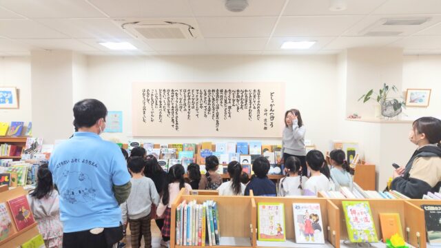 写真：幼稚園生が図書館で読みきかせを聞いています。