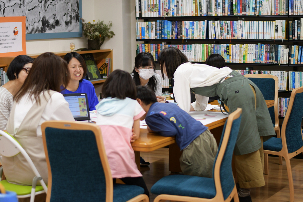 写真:保護者と子どもたちがテーブルに集まって話をしています