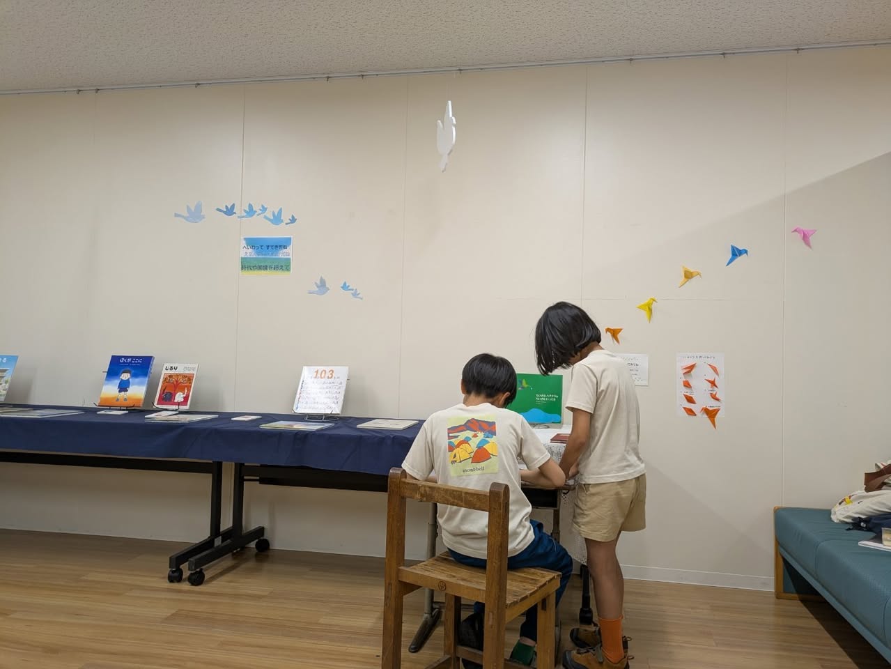 写真：子ども2人が折紙のハチドリを作っている後ろ姿です