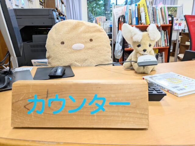 写真：ぬいぐるみが図書館のカウンターに座っています