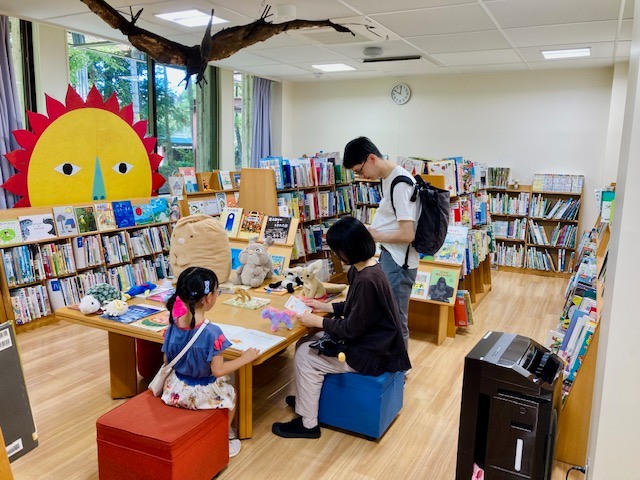 写真：ぬいぐるみを迎えにきた親子が本を見ています