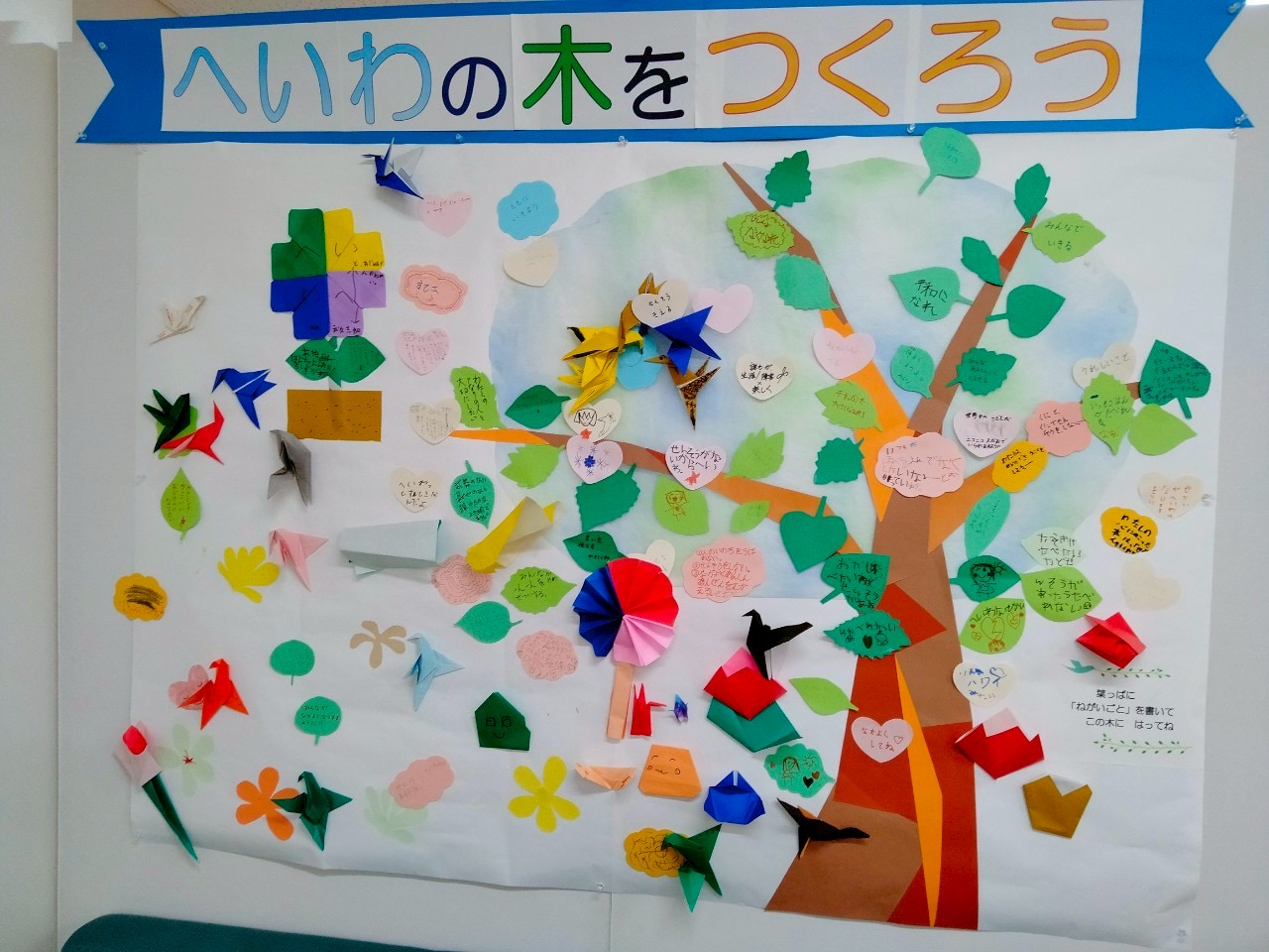 へいわの木に、色とりどりの折り紙の葉っぱや鳥が貼られています。