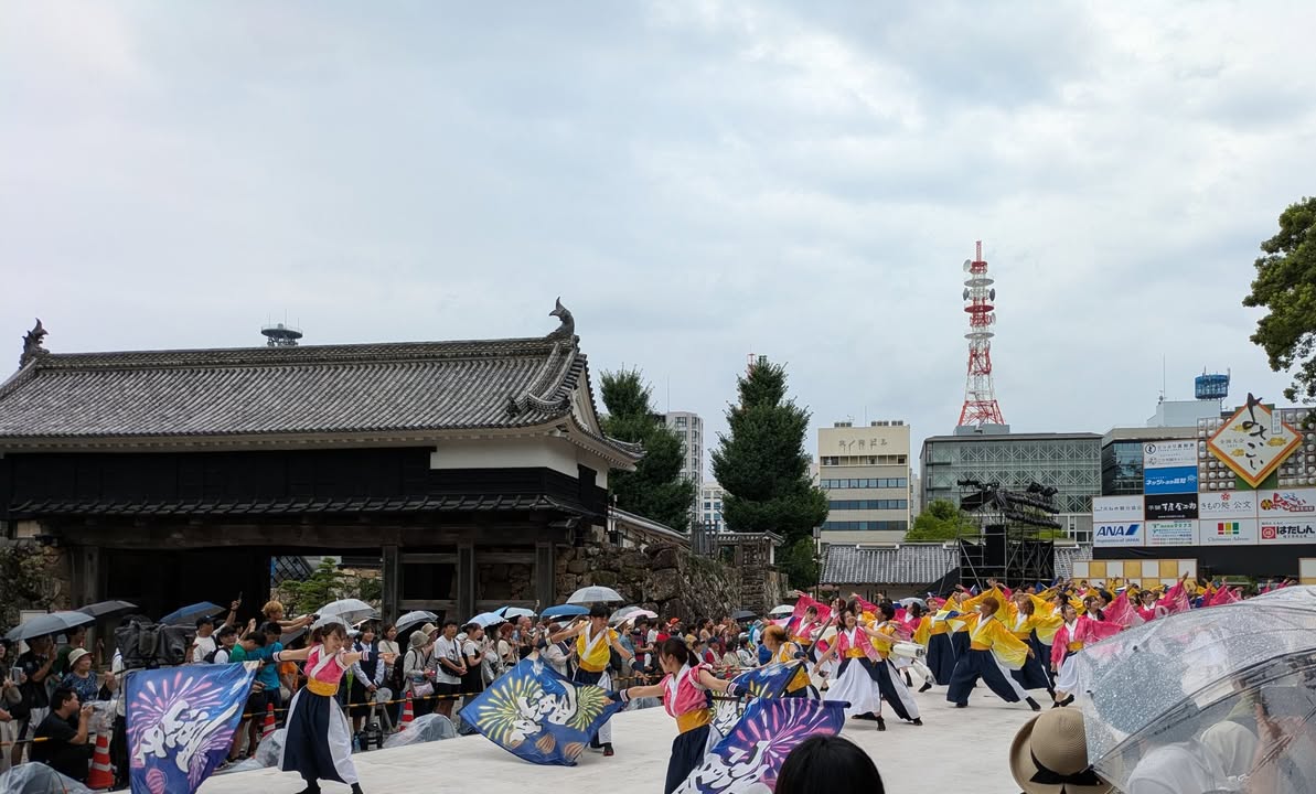 写真：お城の門の前です。踊り子がよさこいを踊っています。