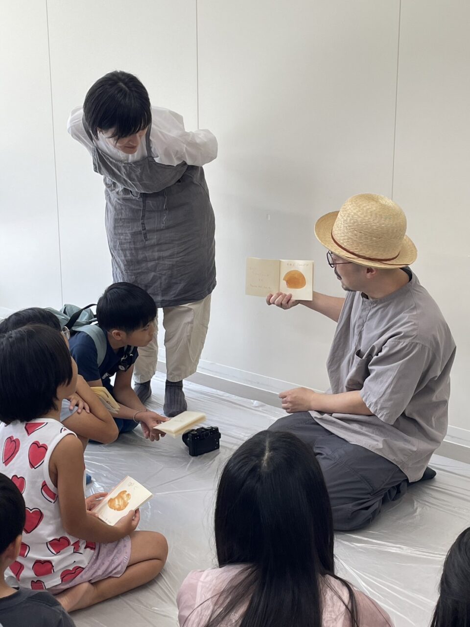 写真：こどもたちの作品をもりとさんが紹介しています。彦坂有紀さんがのぞいています。