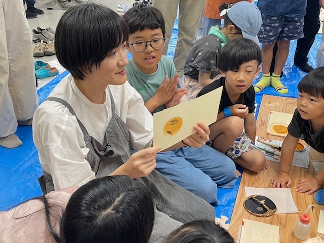 写真：彦坂有紀さんが木版画の説明をしています