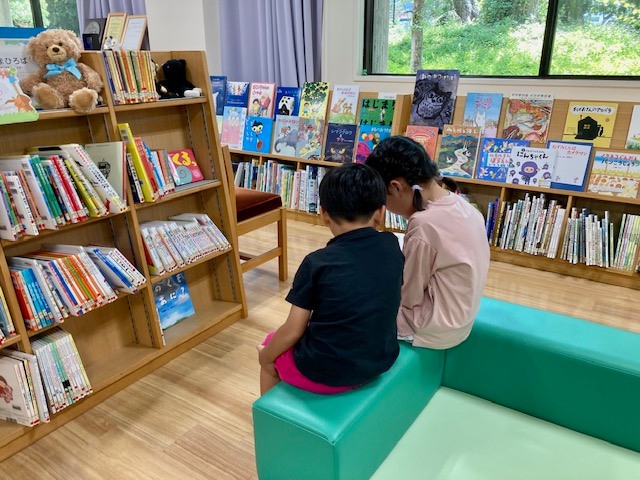 写真：お姉ちゃんが弟に本を読んであげています